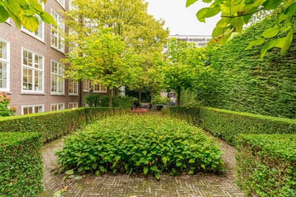 Verzorgde binnentuin met bloemperken, hagen en bomen aan het Lange Voorhout in Den Haag.